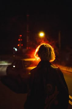 a person standing in the street at night with their back turned to the camera,