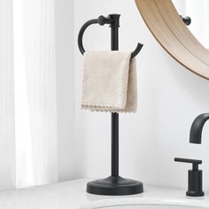 a towel is hanging on a black stand in front of a white sink and mirror