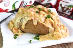 a white plate topped with mashed potatoes covered in gravy and green onions