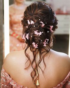 the back of a woman's head with pink flowers in her hair, looking into a mirror