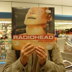 a man holding up a radiohead poster in front of his face