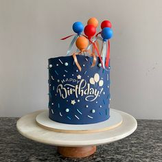 a blue birthday cake with balloons on top