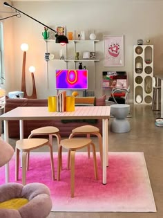 a living room filled with furniture and a pink rug on top of a wooden floor