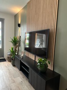 a flat screen tv mounted to the side of a wall next to a wooden floor