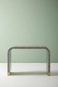 a white and black bench sitting on top of a white floor next to a green wall