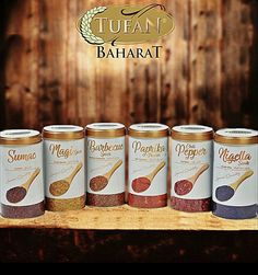 five jars of spices sit on a wooden shelf with the logo of tutan bahart