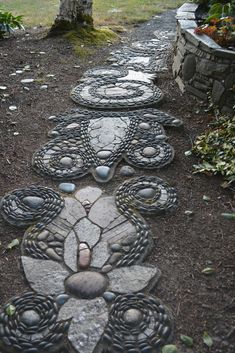 a garden path made out of stones with circles and flowers on the ground next to it