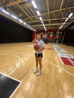 a woman standing on top of a basketball court holding a ball in her right hand