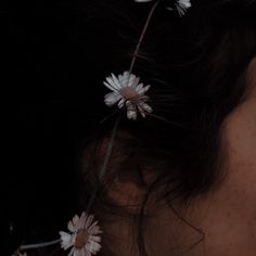 the back of a woman's head with three daisies pinned to her hair