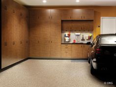 a car is parked in the garage next to some cabinets and cupboards on the wall