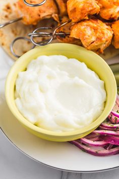 a plate topped with chicken wings and mashed potatoes next to a bowl of sour cream