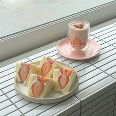 some strawberries are on a plate next to a cup of coffee and a window sill