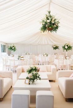 a room with white couches and tables under a tented area that has flowers on it