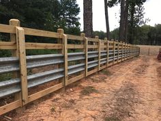 a wooden fence in the middle of a dirt field