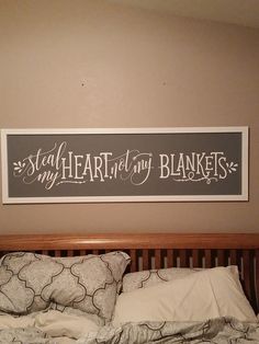 a bed with a wooden headboard and pillow on it, next to a framed sign that says stay heart in my blankets