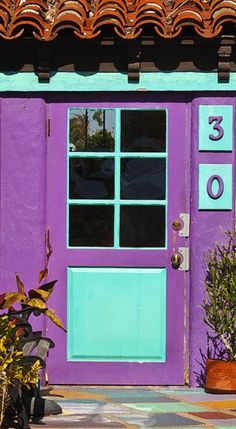 a purple door with numbers painted on it and potted plants next to the door