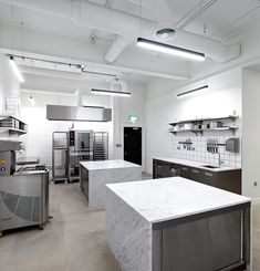 an industrial kitchen with marble counter tops and stainless steel appliances on the walls, along with white tile flooring