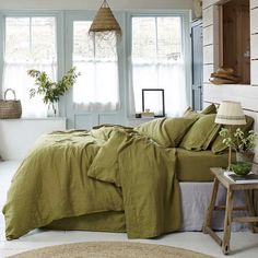 a bed in a bedroom with green linens and pillows on top of the bedspread