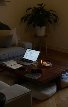 a laptop computer sitting on top of a wooden table in front of a couch and coffee table