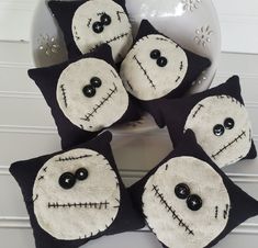 four black and white pillows with faces on them sitting in front of a vase filled with flowers