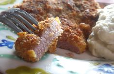 a plate with meat, mashed potatoes and a fork resting on top of it