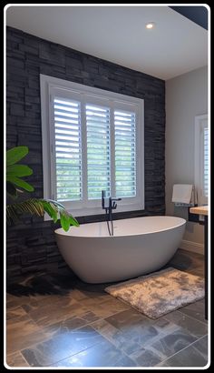 a large white bath tub sitting in a bathroom next to a window with shutters