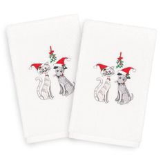 two white towels with cats on them and one has a christmas hat on it's head