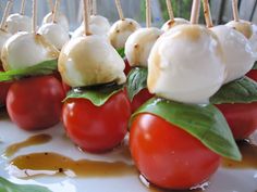 tomatoes and mozzarella on skewers with sauce drizzled on them