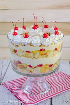 a trifle cake with white frosting and cherries on top, sitting in a glass dish