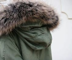 a person wearing a green parka with a large fur collar on their head and hood