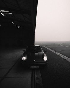 a black and white photo of a car parked on the side of an empty road