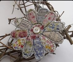 a flower made out of old clothes with buttons on the center and some branches around it