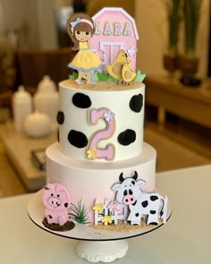 a three tiered cake decorated with farm animals and numbers on it's sides