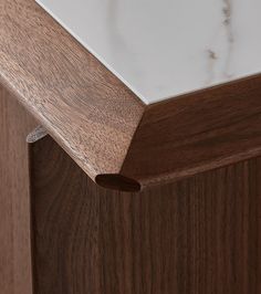 a close up view of the top of a wooden cabinet with white marble on it