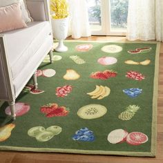 a green area rug with fruits and vegetables on it in front of a couch, window