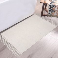 a white bath tub sitting next to a rug on top of a hard wood floor