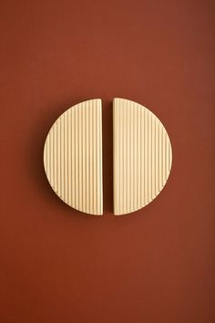 two pieces of wood sitting on top of a red wall next to a white object