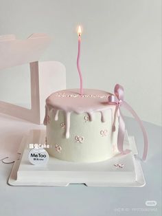 a white cake with pink icing and a single candle