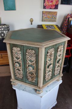 the corner of a room with an ornate green and white box on it's pedestal