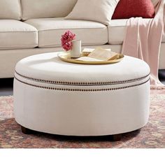 a coffee table with a book and cup on it in front of a white couch