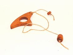 a wooden mask hanging from a string on a white surface with two strings attached to it