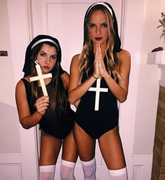 two women dressed in costumes standing next to each other with crosses on their heads and hands