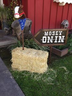 there is a sign that says moosey on it next to hay bales and a cow statue