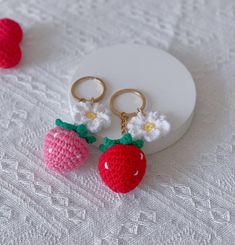 two crocheted strawberry keychains are sitting on a white doily next to each other