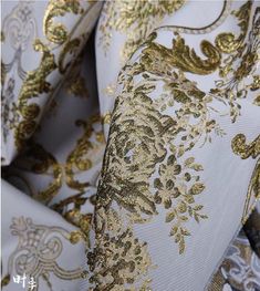 gold and white fabric with large floral designs on the side, as well as an ornate design