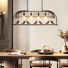 a birdcage chandelier hanging over a dining room table with birds on it