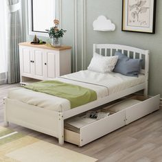 a white bed with drawers underneath it in a room