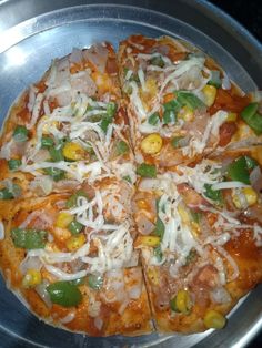 a pizza sitting on top of a metal pan covered in cheese and veggies