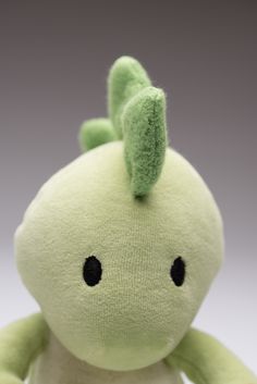 a green stuffed animal sitting on top of a white table