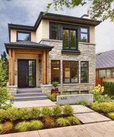 a modern house with two story windows and stone steps leading up to the front door